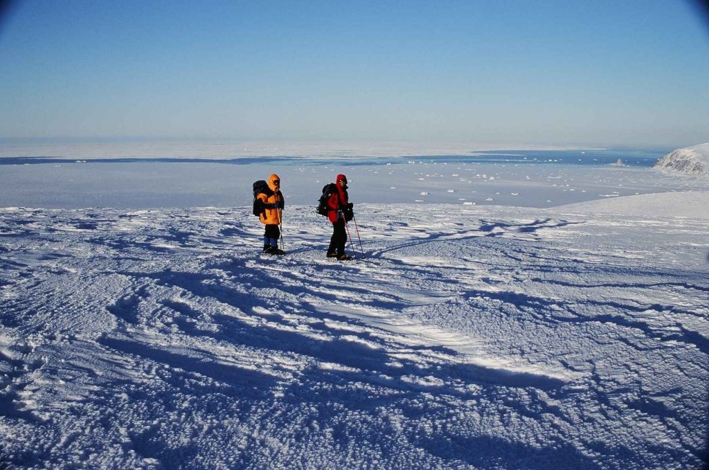 Chris Cooper and John Dunn on Pk 2700 (ft), Coburg Island, overlooking the North Water Polynya and Baffin Bay. The sea stack called Princess Charlotte Monument is prominent at the water-ice boundary on the right 2005 – Sandy Briggs photo.