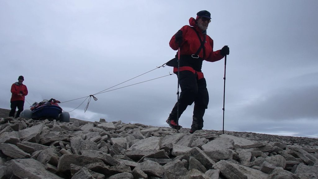 John and Sandy managing the sled-on-wheels down a hillside of broken and pointy rocks near Elwin Bay, eastern Somerset Island 2017 - Sandy Briggs photo.