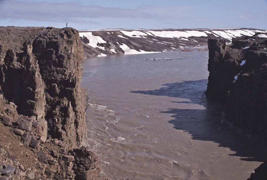 John Dunn above the cliffs of the Hornaday River canyon in full spring flood. Tuktut Nogait National Park 2003 – Sandy Briggs photo.